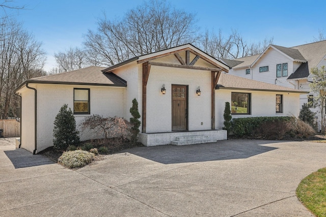 view of front of home with brick siding and roof with shingles