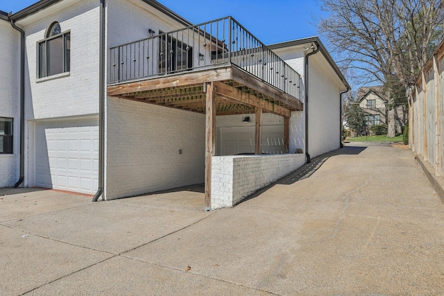 view of property exterior featuring brick siding, concrete driveway, a deck, a carport, and an attached garage