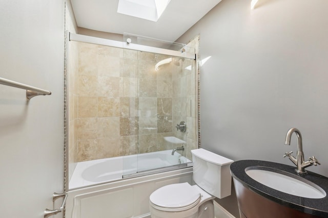 full bathroom with toilet, a skylight, vanity, and bath / shower combo with glass door