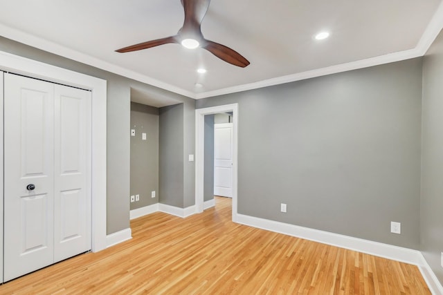 unfurnished bedroom with a closet, baseboards, light wood-style floors, and crown molding