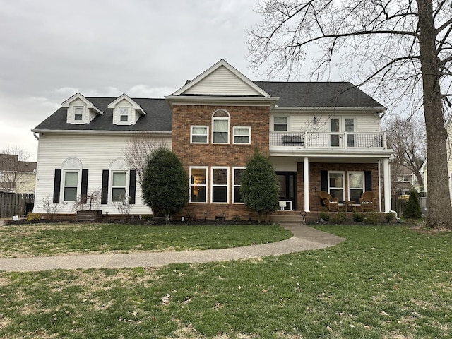 view of front of property with brick siding, a porch, a front yard, and a balcony