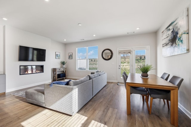 living room with a glass covered fireplace, baseboards, wood finished floors, and recessed lighting