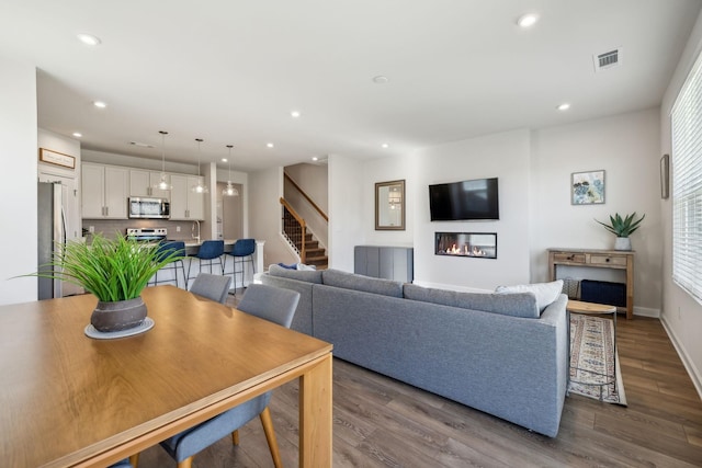 living room featuring dark wood-style floors, stairway, recessed lighting, and visible vents