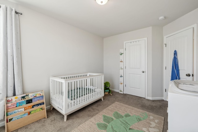 bedroom with a nursery area, washer / clothes dryer, baseboards, and carpet floors