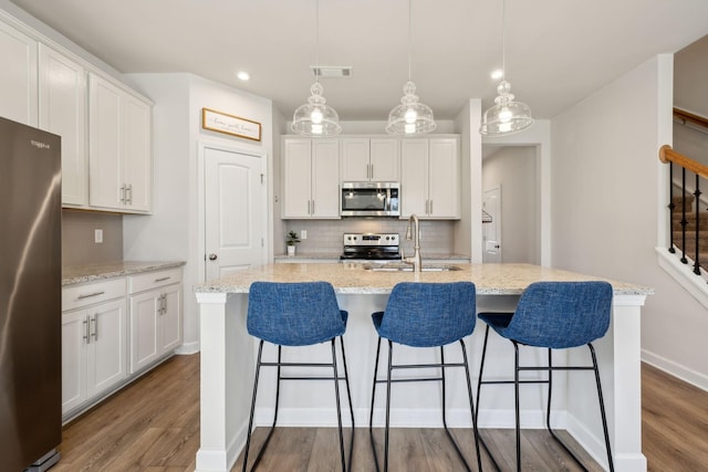 kitchen featuring tasteful backsplash, visible vents, stainless steel appliances, white cabinetry, and a sink