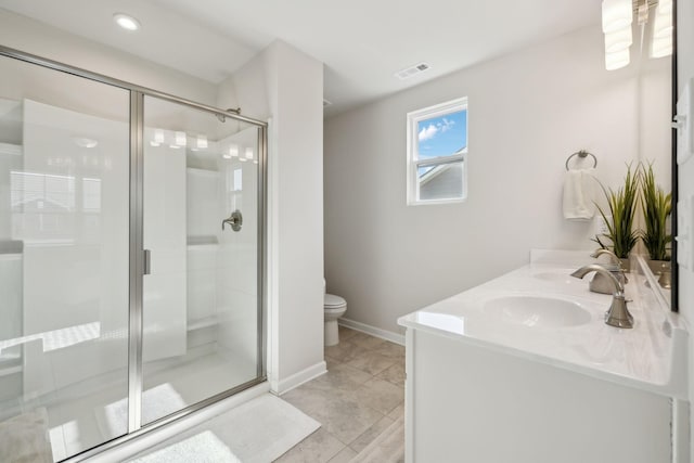 full bathroom featuring visible vents, toilet, double vanity, a stall shower, and a sink