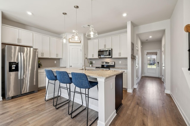 kitchen with tasteful backsplash, wood finished floors, stainless steel appliances, and a sink