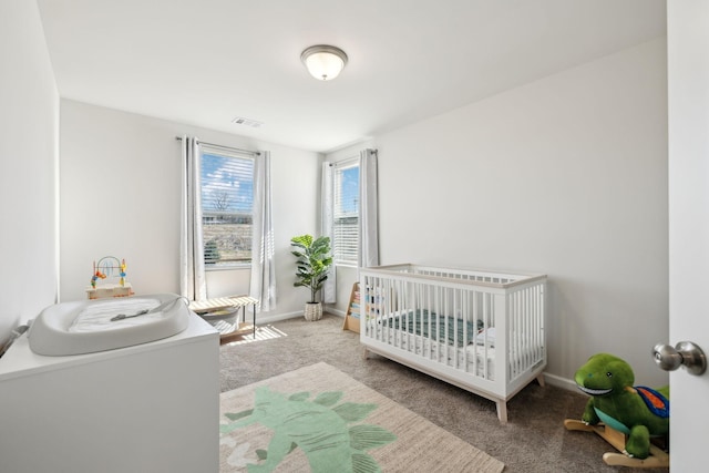 carpeted bedroom featuring visible vents, a crib, and baseboards