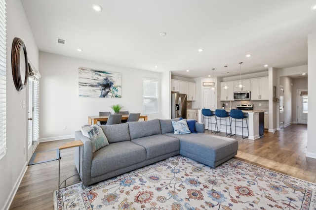 living room featuring visible vents, recessed lighting, light wood-type flooring, and baseboards