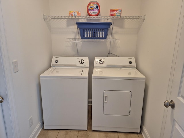 washroom with light tile patterned floors, baseboards, laundry area, and washing machine and clothes dryer