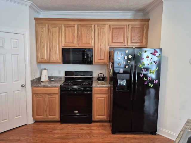 kitchen with ornamental molding, black appliances, light wood-style floors, a textured ceiling, and dark countertops