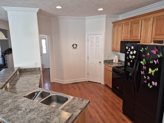 kitchen featuring a sink, black appliances, wood finished floors, and ornamental molding