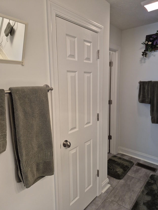 bathroom featuring tile patterned floors, visible vents, baseboards, and a textured ceiling