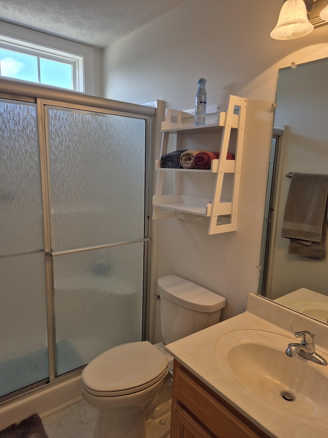 bathroom featuring a shower stall, a textured ceiling, vanity, and toilet