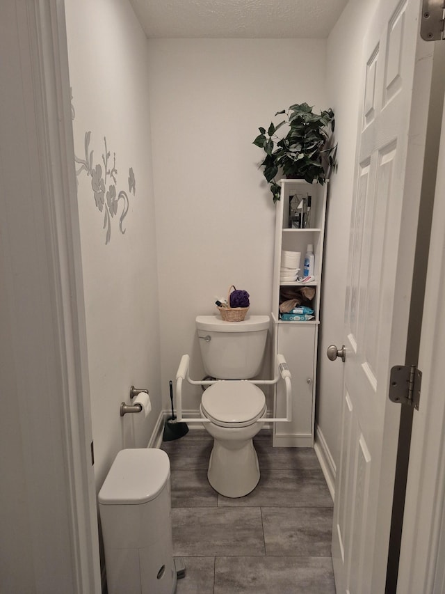 bathroom with toilet, wood finished floors, baseboards, and a textured ceiling