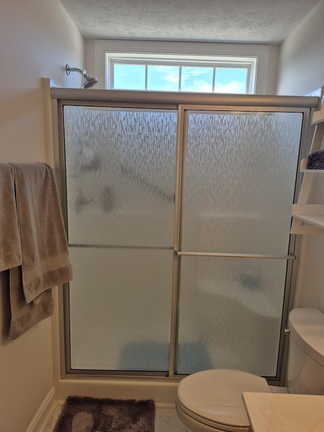 bathroom with a stall shower, toilet, and a textured ceiling