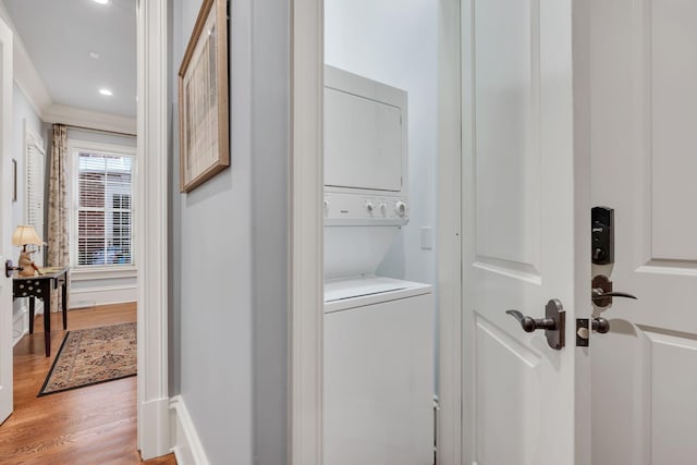 clothes washing area featuring laundry area, stacked washer and dryer, recessed lighting, and light wood-type flooring