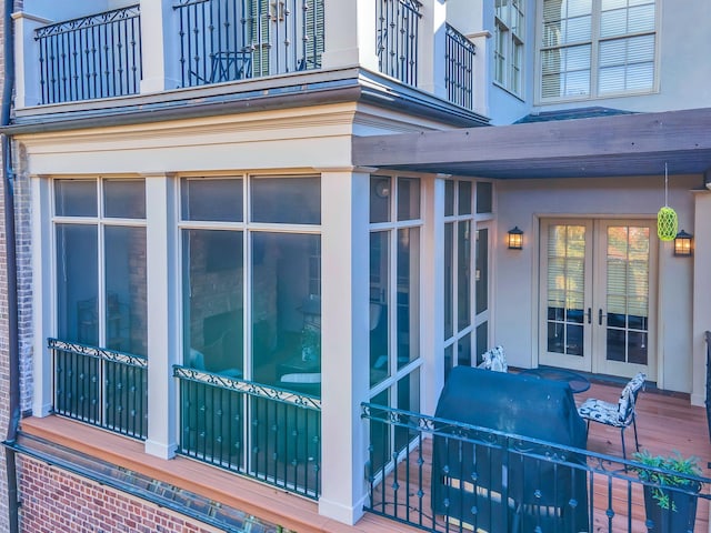 view of side of property featuring french doors, a balcony, and stucco siding