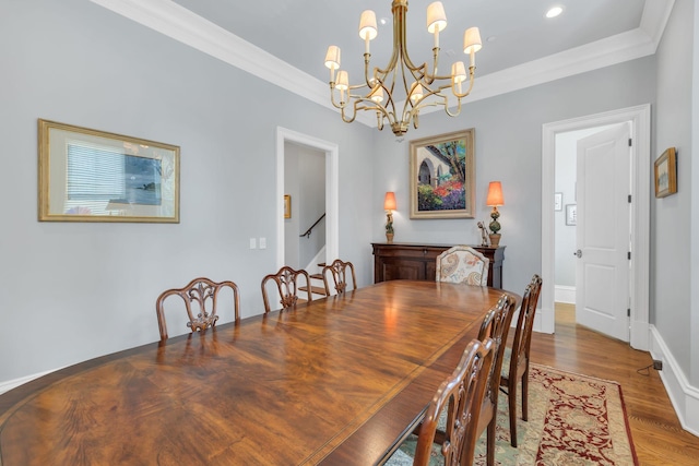 dining room featuring an inviting chandelier, crown molding, wood finished floors, and baseboards