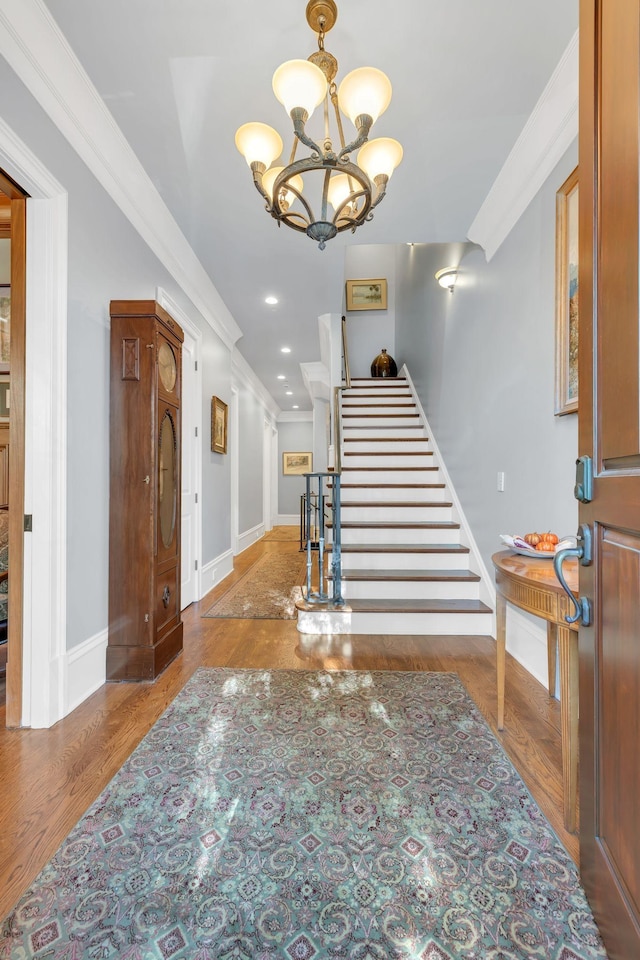 foyer featuring a chandelier, wood finished floors, stairs, and ornamental molding