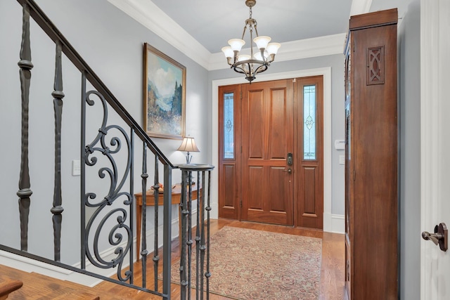 foyer with a notable chandelier, stairs, light wood-style floors, and ornamental molding