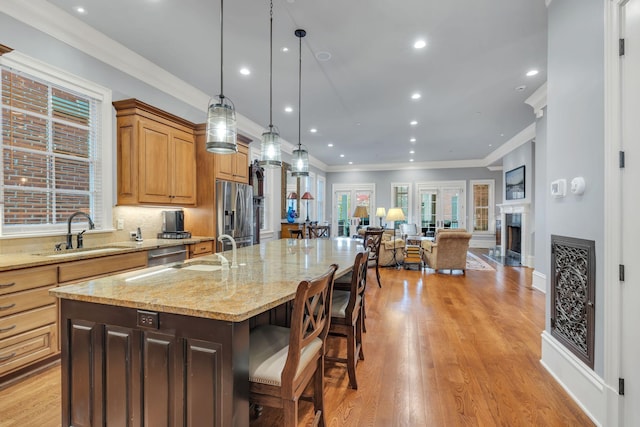 kitchen with a sink, a spacious island, open floor plan, stainless steel appliances, and a fireplace