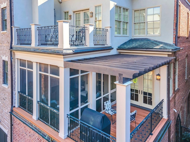 view of side of home featuring a balcony, french doors, and roof with shingles