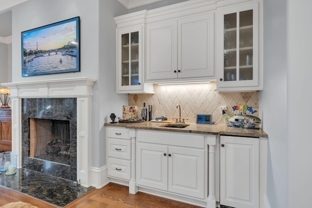 bar with decorative backsplash, a premium fireplace, wood finished floors, and a sink