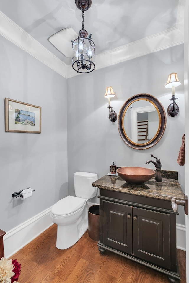 bathroom featuring vanity, wood finished floors, toilet, ornamental molding, and a notable chandelier