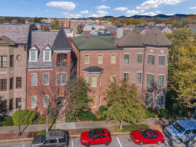 view of building exterior with a residential view, a mountain view, and uncovered parking