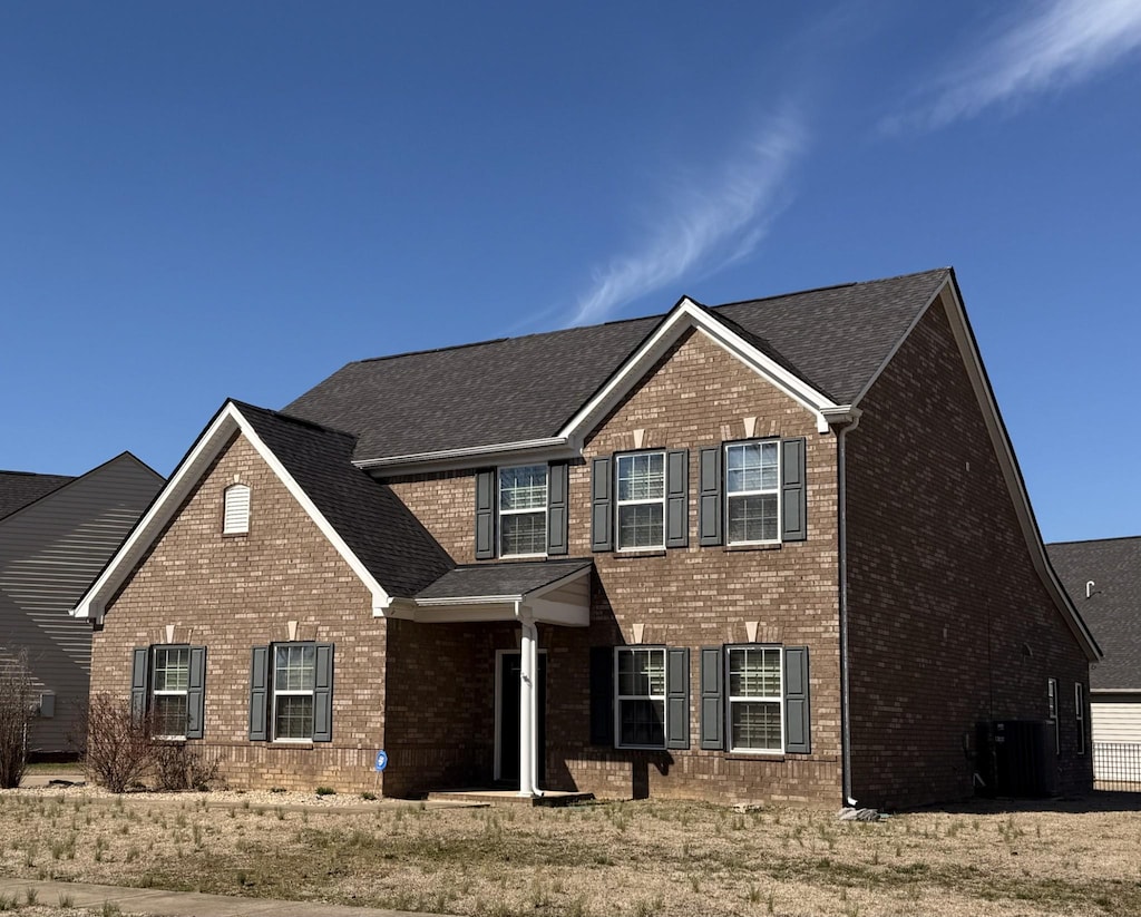 view of front of home featuring brick siding and central AC