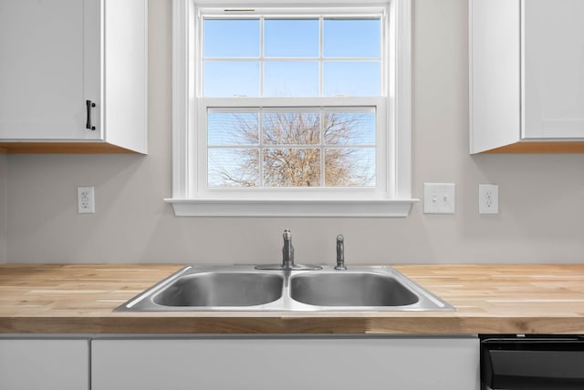 kitchen featuring white cabinetry, butcher block counters, and a sink