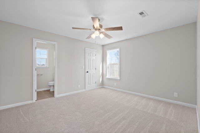 unfurnished bedroom featuring carpet flooring, multiple windows, visible vents, and baseboards