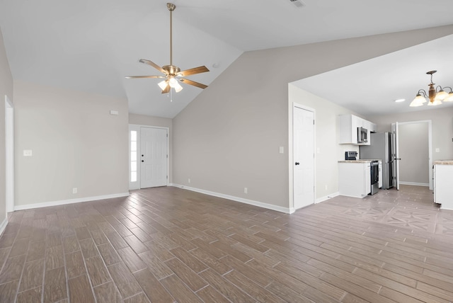 unfurnished living room with ceiling fan with notable chandelier, lofted ceiling, baseboards, and wood finished floors