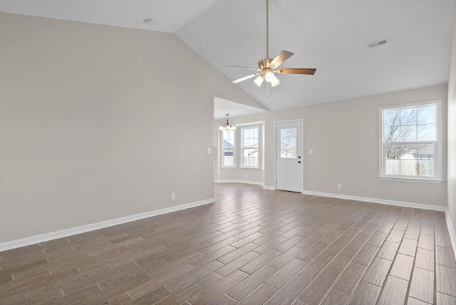 spare room with baseboards, visible vents, high vaulted ceiling, wood tiled floor, and ceiling fan with notable chandelier