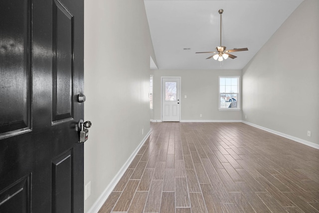 foyer with dark wood finished floors, ceiling fan, baseboards, and lofted ceiling