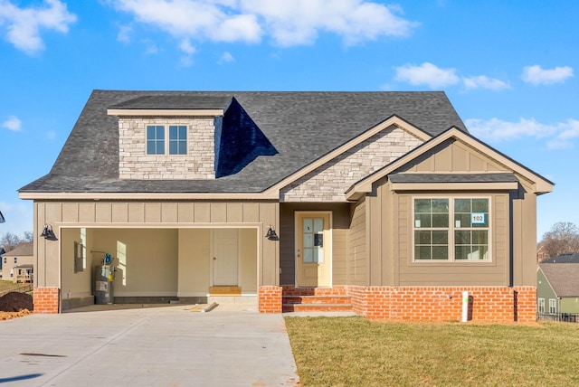 view of front of property featuring driveway, a front lawn, electric water heater, board and batten siding, and brick siding