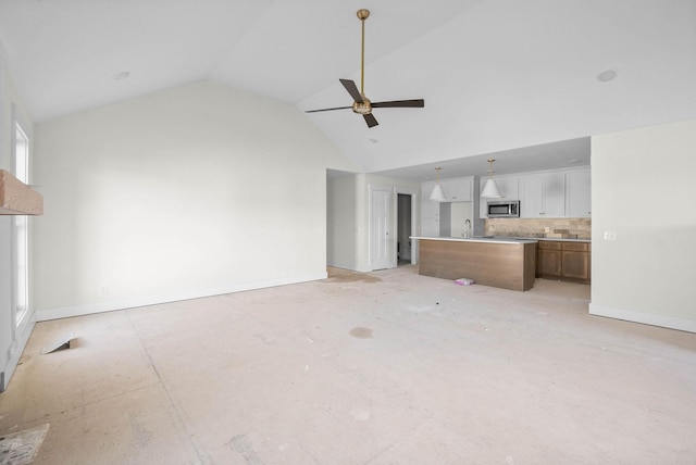 unfurnished living room featuring ceiling fan, high vaulted ceiling, baseboards, and a sink