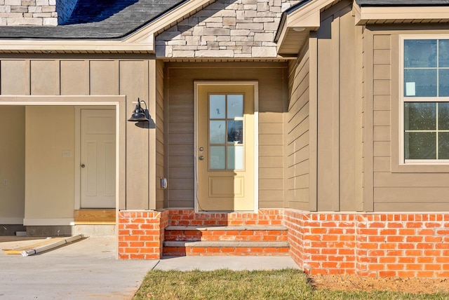 doorway to property with brick siding, board and batten siding, and a shingled roof