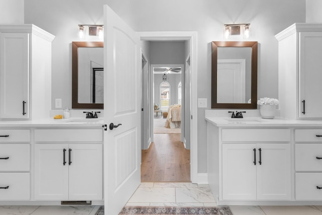 ensuite bathroom with a sink, two vanities, and marble finish floor