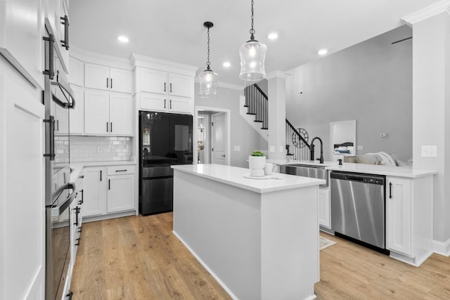 kitchen featuring decorative light fixtures, light wood-type flooring, light countertops, decorative backsplash, and appliances with stainless steel finishes