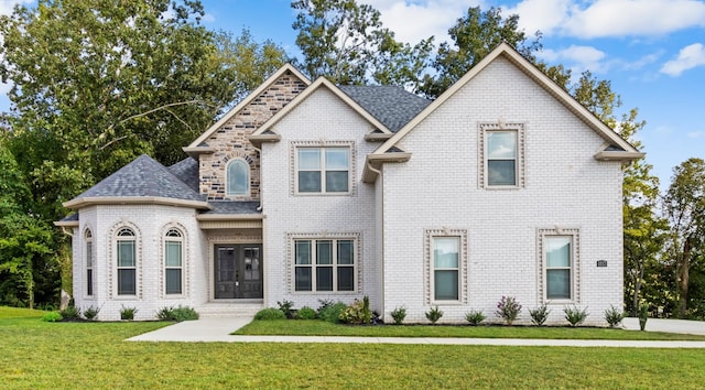 view of front of house with brick siding, a front lawn, and a shingled roof