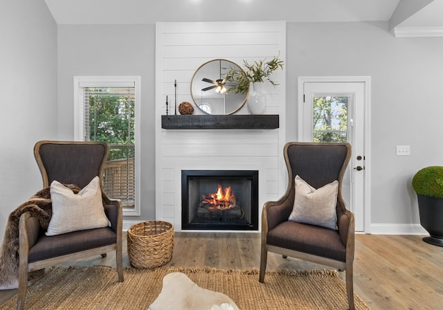 sitting room with baseboards, a large fireplace, and wood finished floors