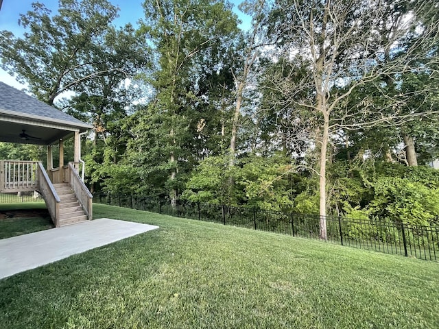 view of yard with stairway, ceiling fan, and fence