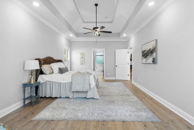 bedroom featuring wood finished floors, baseboards, a tray ceiling, recessed lighting, and crown molding