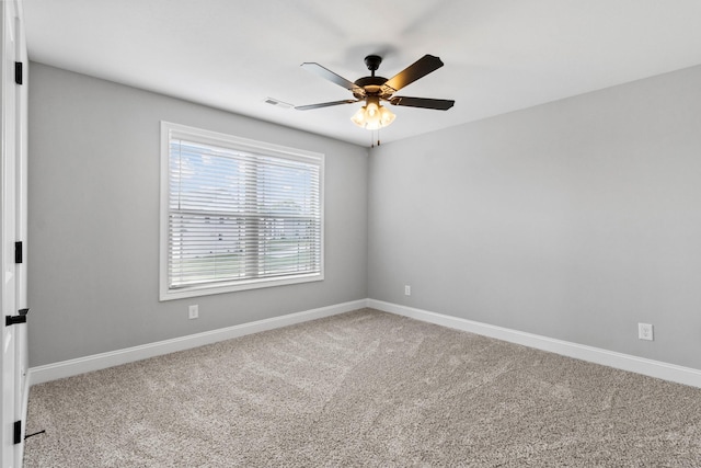 carpeted spare room featuring visible vents, baseboards, and ceiling fan