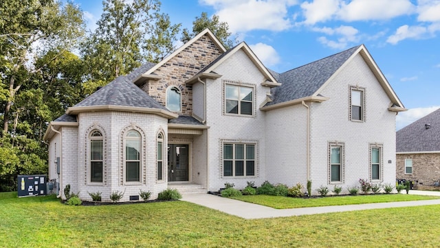 view of front of home featuring brick siding, a front lawn, and roof with shingles