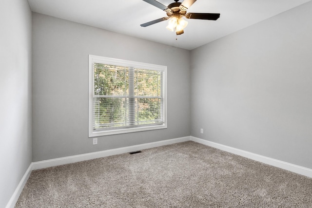 carpeted empty room featuring visible vents, a ceiling fan, and baseboards