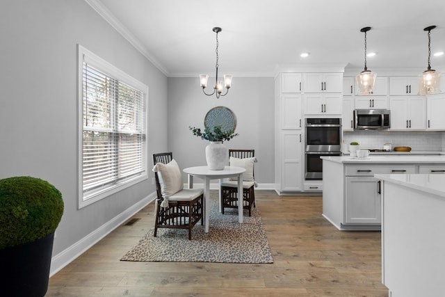 kitchen featuring visible vents, backsplash, crown molding, stainless steel appliances, and white cabinetry