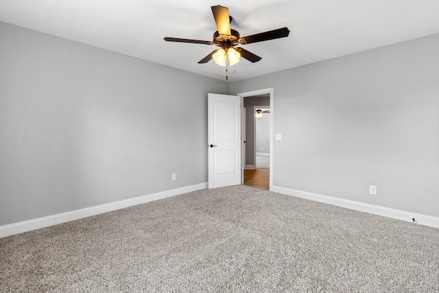 carpeted spare room featuring a ceiling fan and baseboards